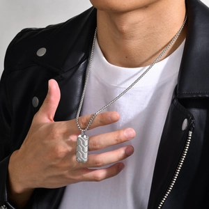 Detail shot of men's stainless steel necklace with geometric tire pattern on leather jacket