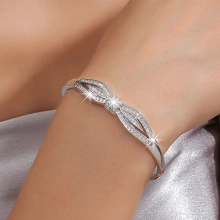Detailed view of silver bow-knot bracelet with micro-paved zircons on a silk background