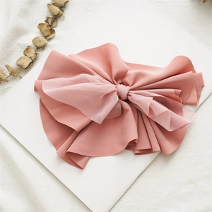Detail shot of a dusty rose fabric bow spring hair clip on a white decorative platform