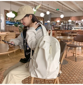 White large capacity water-resistant backpack shown in a casual cafe lifestyle setting