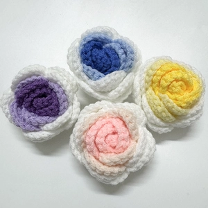 Detail of four colorful handmade crochet rose flower heads in purple, blue, yellow, and pink