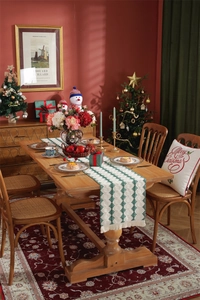 Close-up of white and green knitted Christmas table runner with festive tassel fringe details