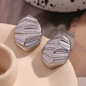 Gros plan de boucles d'oreilles sculptées argentées sur un plateau en céramique