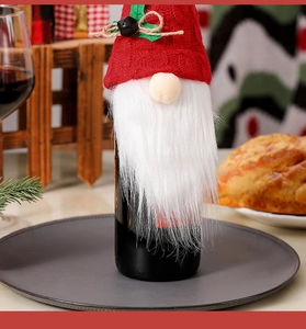 Close-up of a festive knitted Christmas gnome wine bottle cover with a bell and twine