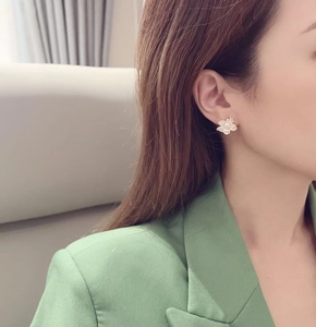 Detail of freshwater pearl earring featuring a frosted flower design on female model