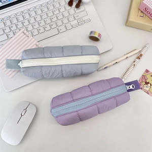 Detailed view of blue and purple quilted pencil cases on a minimalist office desk