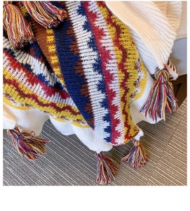 Detail of woven shawl featuring colorful geometric waves and vibrant fringe tassels on edges
