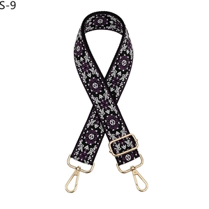 Detail of ethnic style purple woven bag strap with white geometric patterns and gold clips