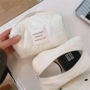 Détail de la trousse de maquillage matelassée crème avec broderie florale et intérieur