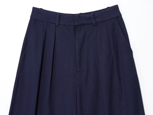 Detail of dark blue pleated pants showing waist design and twill fabric texture