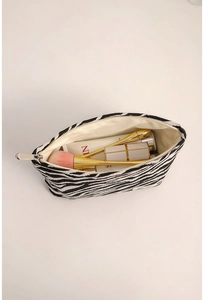 Top view of zebra print canvas cosmetic bag showing spacious interior with makeup tools