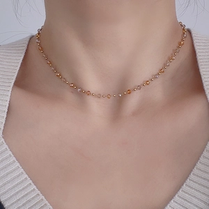 Close-up of beaded necklace with amber crystal facets and gold accents on a model