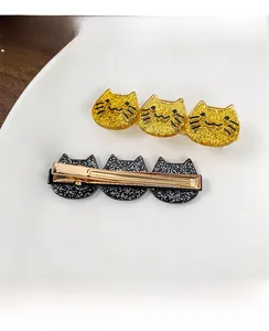 Detailed view of cat-shaped acetate hair clips with yellow and black glitter finishes