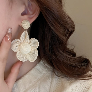 Detailed macro view of bohemian raffia flower earrings featuring intricate woven textures