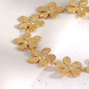 Close-up of 18K gold plated stainless steel daisy chain bracelet on white rock