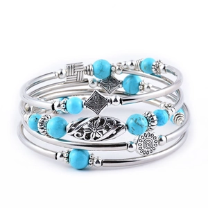 Detailed view of layered bohemian bracelet with turquoise beads and silver metal charms