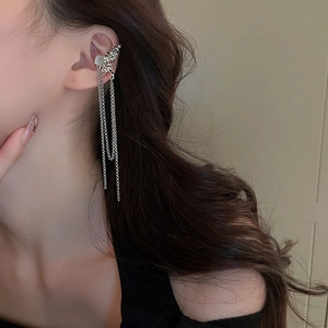Détail d'un ear cuff papillon argenté avec de longs glands à double chaîne sur l'oreille