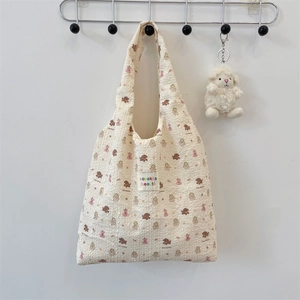 Detail of waffle fabric shoulder bag featuring cute embossed animal patterns and logo