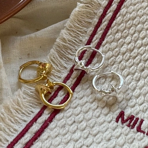 Detail of gold and silver hoop earrings with a twisted fluid texture on woven fabric