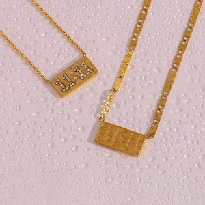 Detail of two 11:11 rectangular gold necklaces with zircon inlay on pink water texture