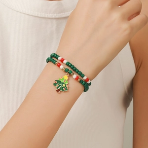 Close-up of a Christmas beaded bracelet featuring a festive green tree enamel charm