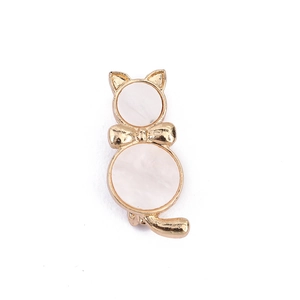 Close-up of golden cat brooch with white mother of pearl inlay and delicate bow detail