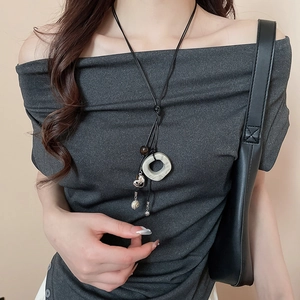 Detailed view of an ethnic necklace featuring a green ring and heart pendant on a black cord