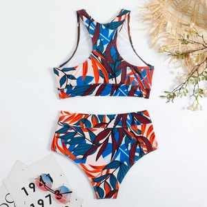 Flat lay of high waist two-piece bikini with vibrant tropical leaf print and beach props