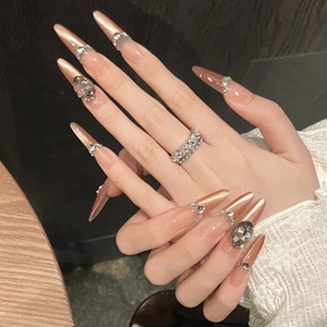 Detail of nude stiletto press-on nails with rose gold cat eye finish and luxury rhinestones