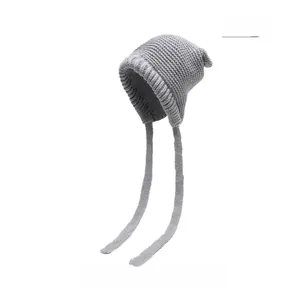 Detailed view of grey knitted earflap hat with thick texture and long straps