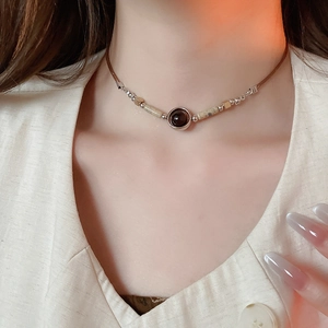 Detail of vintage bohemian choker with dark gemstone pendant and beige stone beads