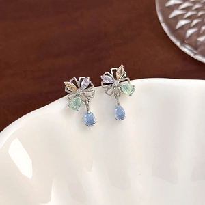Macro shot of silver earrings with colorful zircon flower clusters and blue drop pendants