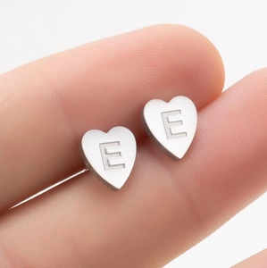 Gros plan sur une boucle d'oreille cœur en acier brossé avec gravure de la lettre E