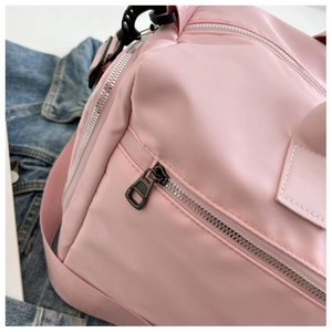 Detailed close-up of pink gym bag featuring a smooth nylon fabric and silver side zipper