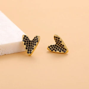 Macro detail of heart-shaped gold stud earrings with pave-set black crystals