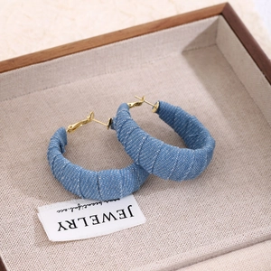 Vintage blue denim wrap hoop earrings on a minimalist wooden tray with gold posts