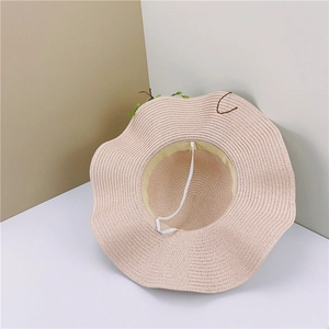 Close-up of wavy brim straw sun hat featuring woven texture and white elastic wind rope