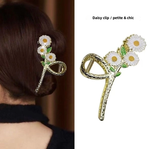 Detail of a floral hair claw clip with white daisies and golden metallic tassels