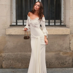 Detail of white V-neck dress with lace stitching and ruffle cuffs on long sleeves