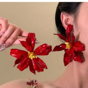Macro shot of oversized red acrylic flower earrings with smooth glossy petals