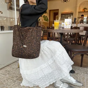 Detail of classic leopard print tote bag with metallic oval logo and durable canvas texture