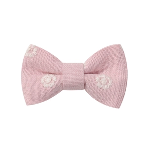 Detailed close-up of pink fabric hair clip with white embroidered floral patterns