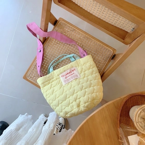 Détail du sac bandoulière matelassé jaune avec motifs cœurs et sangles contrastées