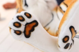 Macro detail of plush tiger paw showing soft orange fur and realistic brown claw pads