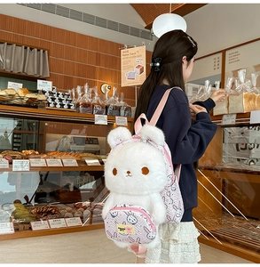 Detail of cute white plush rabbit backpack with pink patterned front zipper pocket