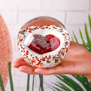 Macro detail of handmade crystal ball featuring a red heart and gold leaf flakes
