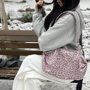 Borsa tote scamosciata con stampa leopardata rosa indossata su una panchina al parco