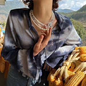 Close-up of layered necklace with white pearls, silver chains, and lion head pendant