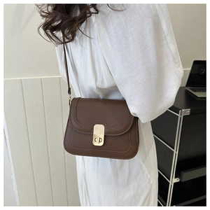 Detail of dark brown leather crossbody bag with wave flap and gold turn-lock closure