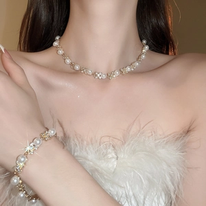 Dettaglio di elegante set collana e bracciale in oro con perle e fiocchi di cristallo